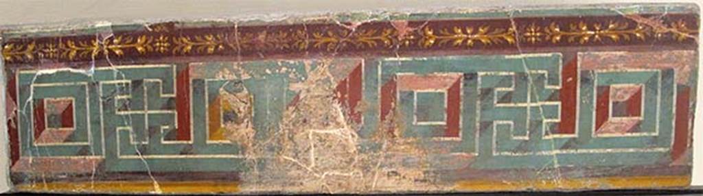 Villa dei Papiri, Herculaneum. Atrium (c). Meander fresco.
Now in Naples Archaeological Museum. Inventory number 8548.
According to Esposito, the upper part of the atrium's walls was decorated with a perspective meandering frieze, of which a fragment was recovered during the eighteenth-century explorations.
The relevance of this piece to the decoration of the atrium, for a long time discussed, can now be confirmed by the discovery of a small fragment of painted plaster that exhibits a purple bottom band, next to which is painted a green band and adorned with a stylized floral element with eight petals, fielded in orange with cream white highlights.
The motive of the perspective meander is very frequent in the pavement and parietal decorations of the late Republican age. In particular it is often used as a frieze placed to crown the median area.
See Esposito D., 2010. Le pitture della Villa dei Papiri ad Ercolano in La Villa Romaine de Boscoreale et ses Fresques. Édicions errance: Musée royal de Mariemont. p. 214, fig. 6.